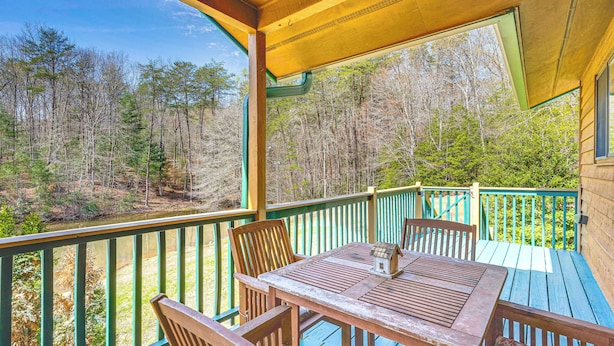 A wooden deck with a table and chairs, overlooking a forested area. - Murphy Cabin w/ Deck, Grill & Private Pond! (Murphy)