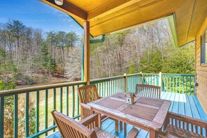 A wooden deck with a table and chairs, overlooking a forested area. - Murphy Cabin w/ Deck, Grill & Private Pond! (Murphy)