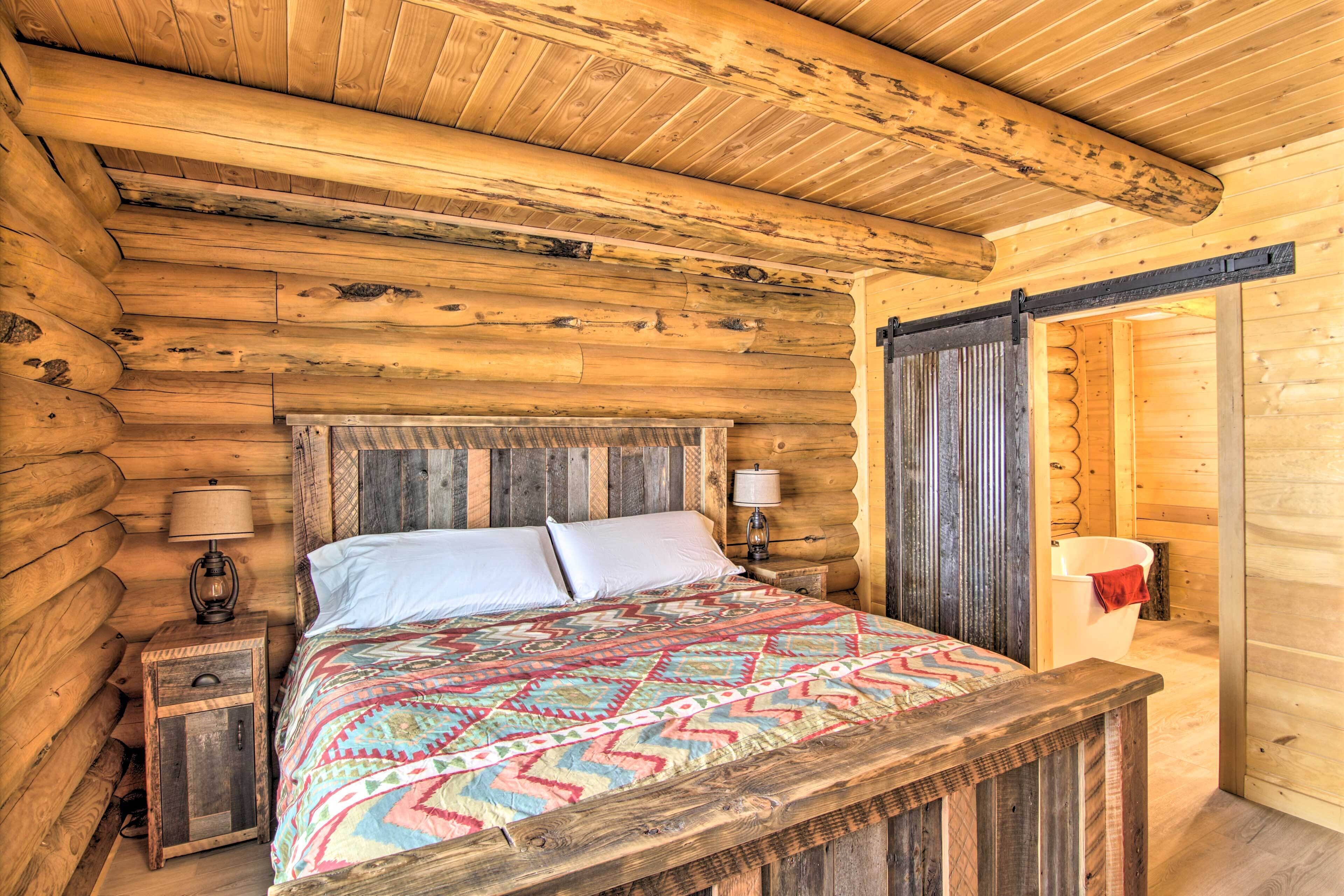 Ein Schlafzimmer in einer Blockhütte mit einem hölzernen Bett, zwei Nachttischlampen und einem Nachttisch aus Holz.