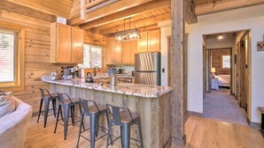 Eine geräumige Küche mit Holzausstattung, einer großen Kochinsel mit Barhocker und einem modernen Kühlschrank.