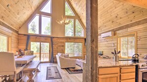 Ein geräumiges Holzblockhaus-Interieur mit Essbereich, Sofa und Küche.