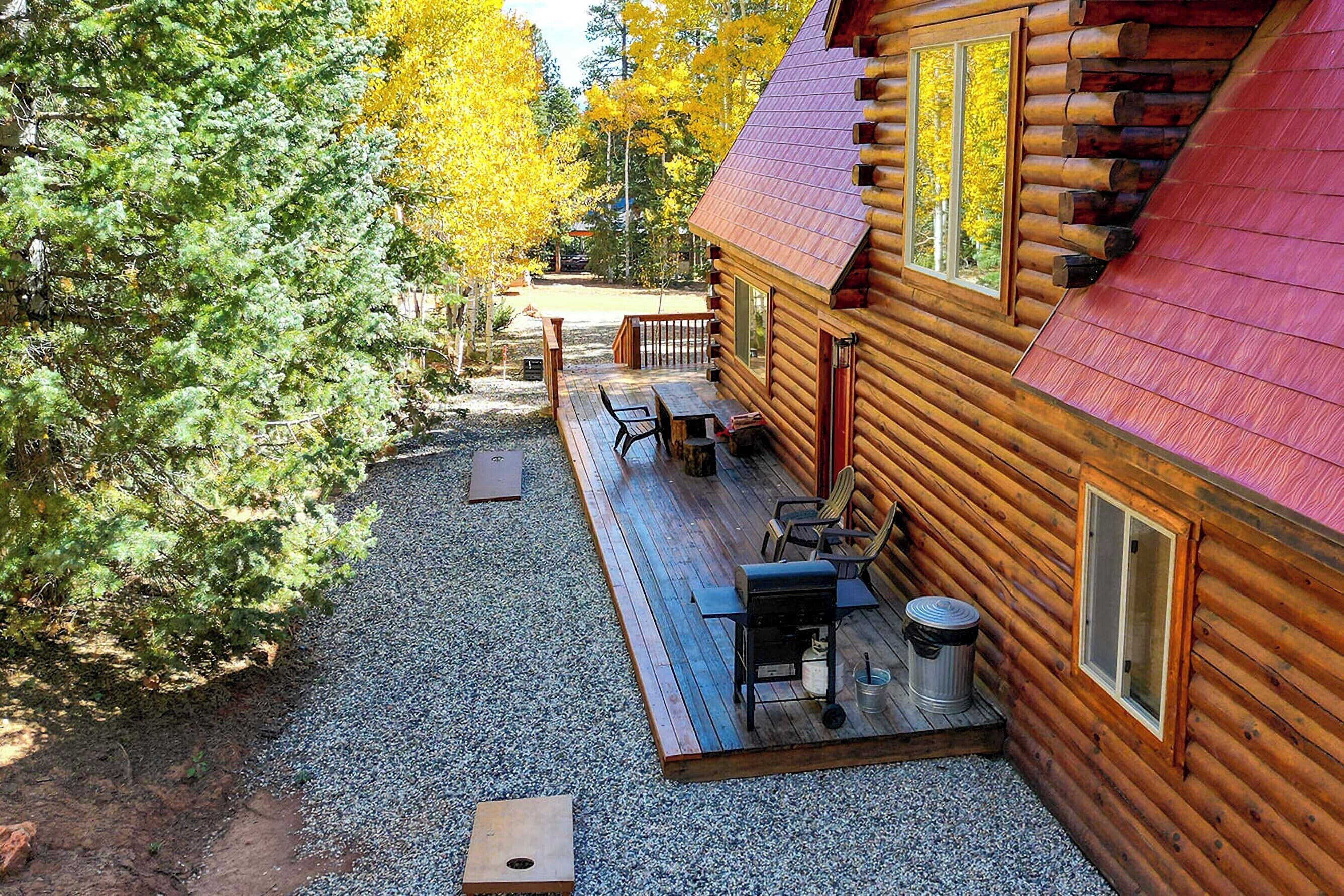 A log cabin with a deck, outdoor seating, and a gravel path.