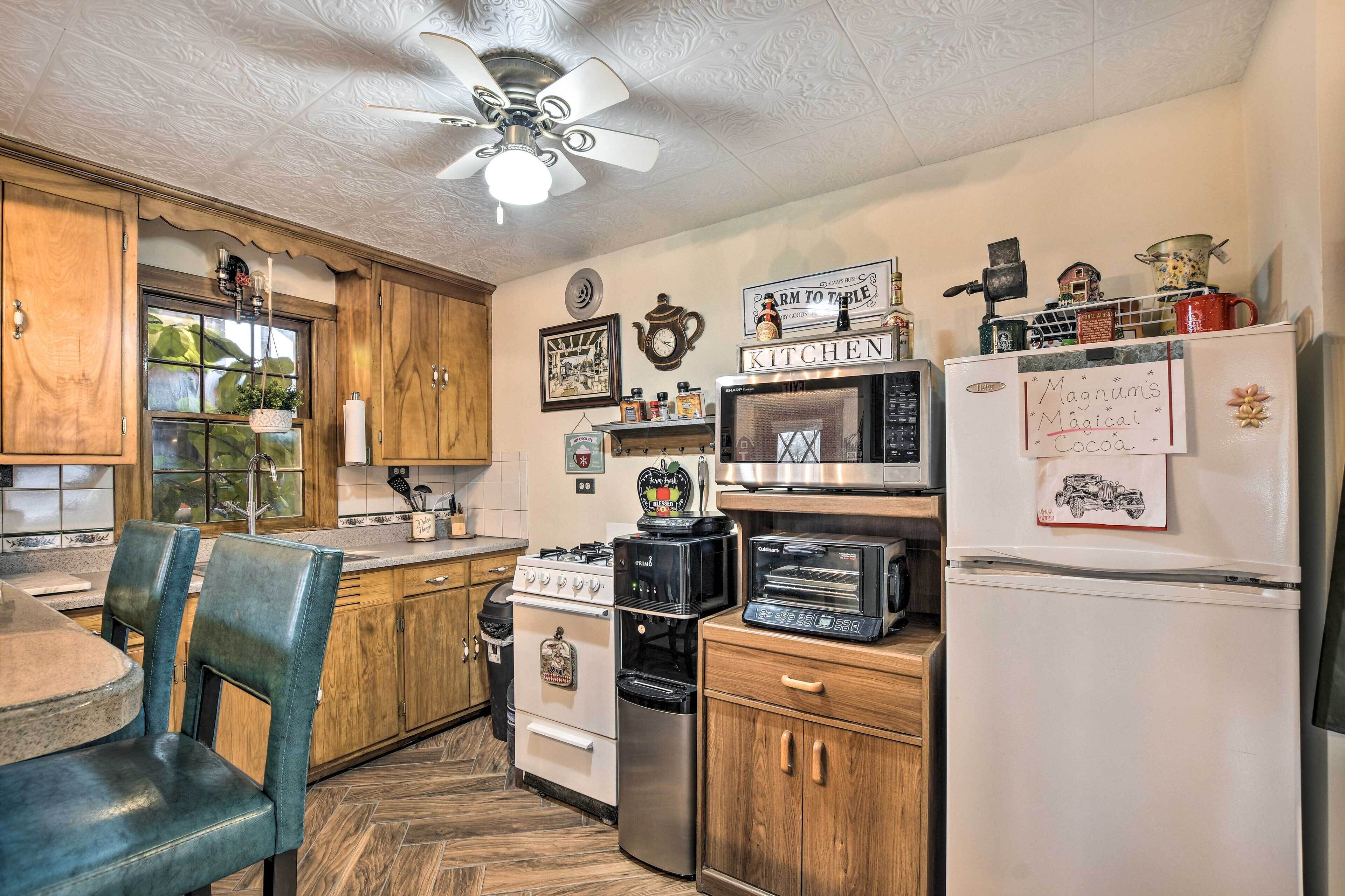 A kitchen with wooden cabinets, a gas stove, a microwave, a toaster, and a refrigerator.