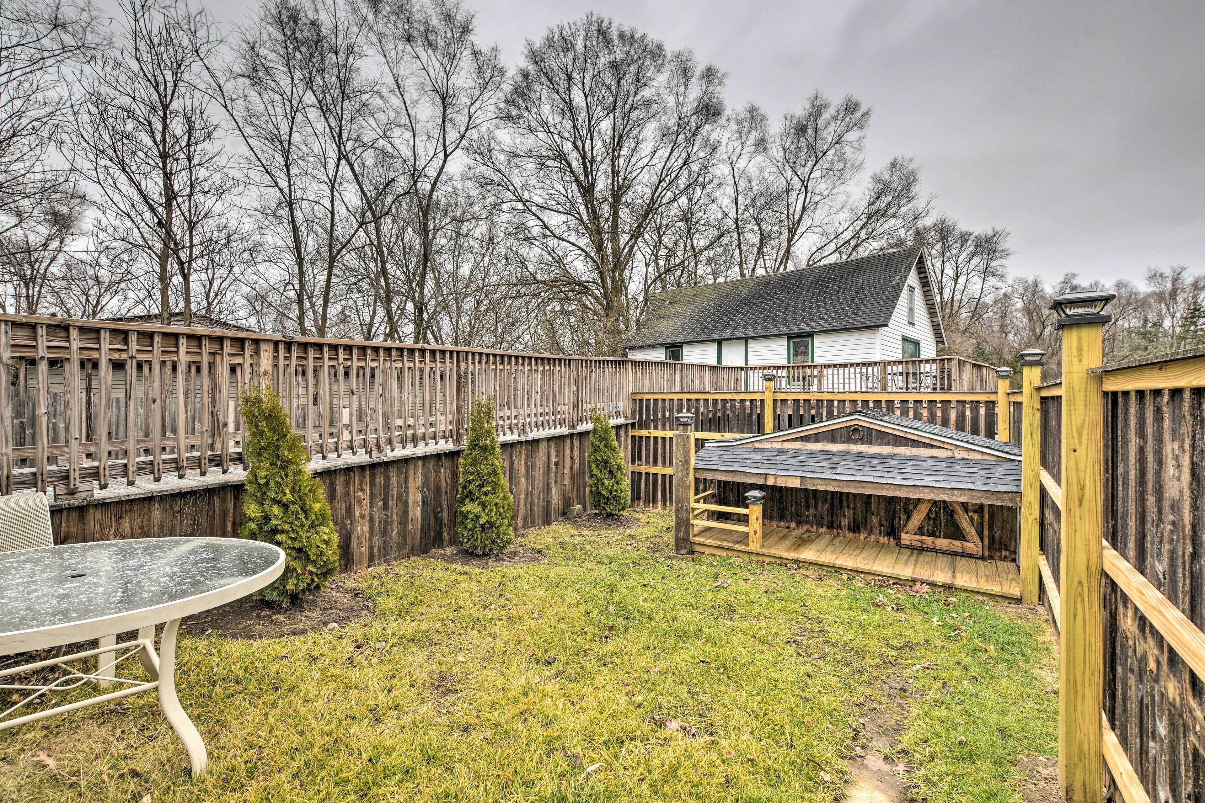 A backyard with a wooden fence, a small wooden structure, and a table.
