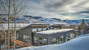 Une maison moderne avec de grandes fenêtres et un paysage enneigé en arrière-plan.
