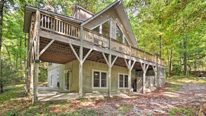 A two-story wooden cabin with a balcony, surrounded by trees and a leaf-covered ground. - 2 Mi to Sapphire Resort: Home w/ Hot Tub & Games! (Sapphire)