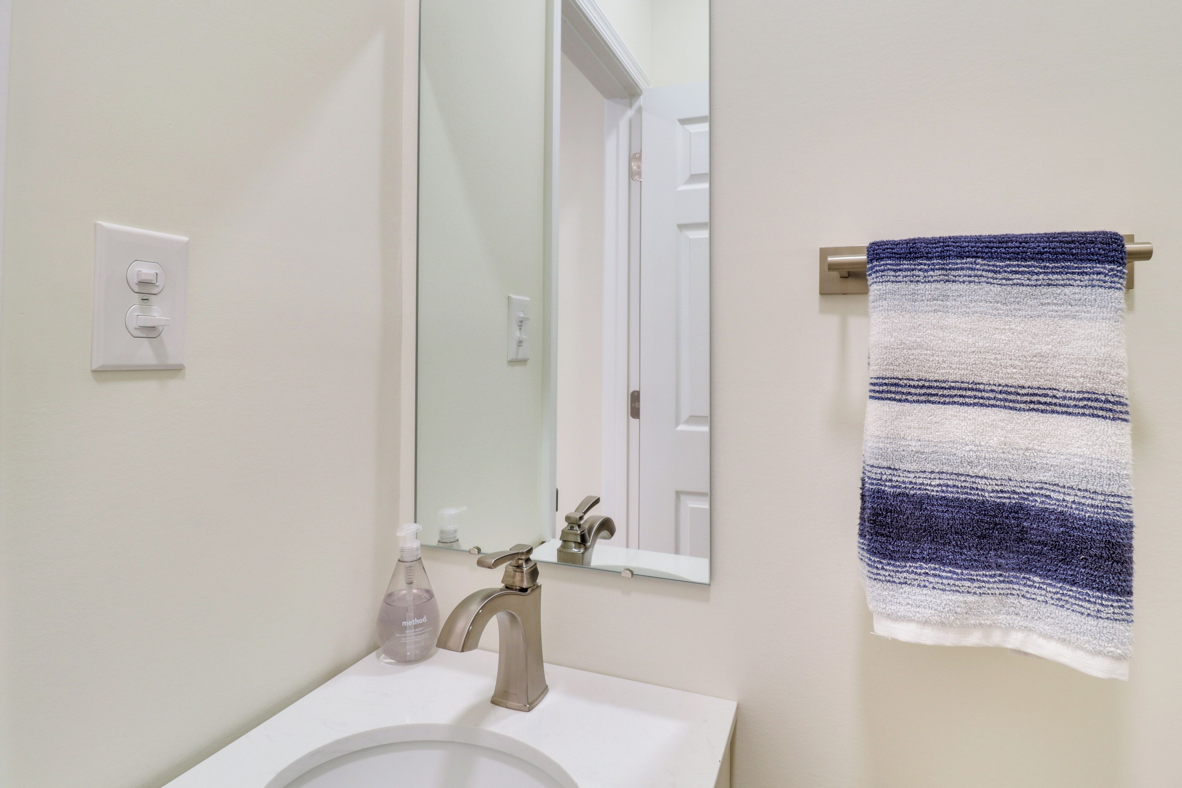 A bathroom with a white sink, a mirror, and a towel rack with a striped towel.