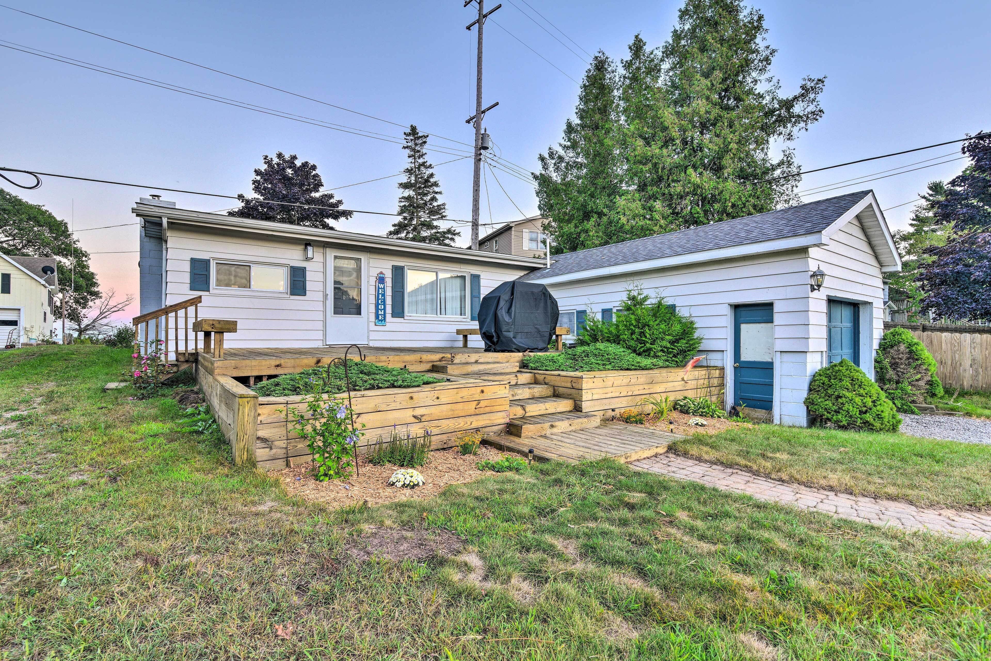 A residential property with a front yard, wooden steps leading to a porch, and a covered outdoor area.