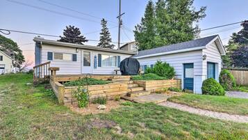 A residential property with a front yard, wooden steps leading to a porch, and a covered outdoor area.