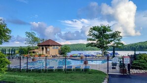 Une piscine avec des chaises longues, un petit bâtiment et une vue sur le lac.