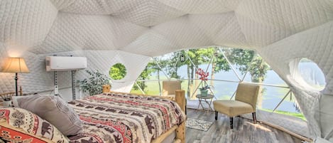 A cozy tent-style bedroom with a bed, seating area, and a view of the outdoors.
