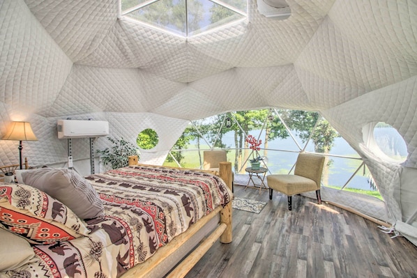 A cozy tent-style bedroom with a bed, seating area, and a view of the outdoors.