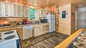 A wooden cabin kitchen with a stove, refrigerator, microwave, and wooden cabinets. - Big Lake Getaway w/ Private Beach + Fire Pit! (Cushing)