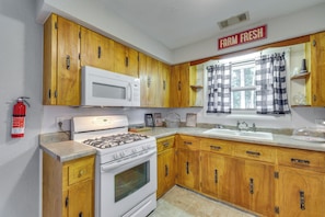 A kitchen with wooden cabinets, a white stove, a microwave, and a sink. - 4 Mi to Dtwn! Ozarks Hideaway w/ Furnished Deck (Eureka Springs)
