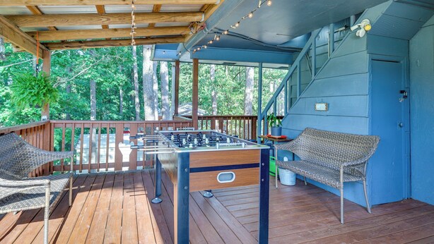 Eine Holzterrasse mit einem Kicker, Korbstühlen und einer blauen Wand.