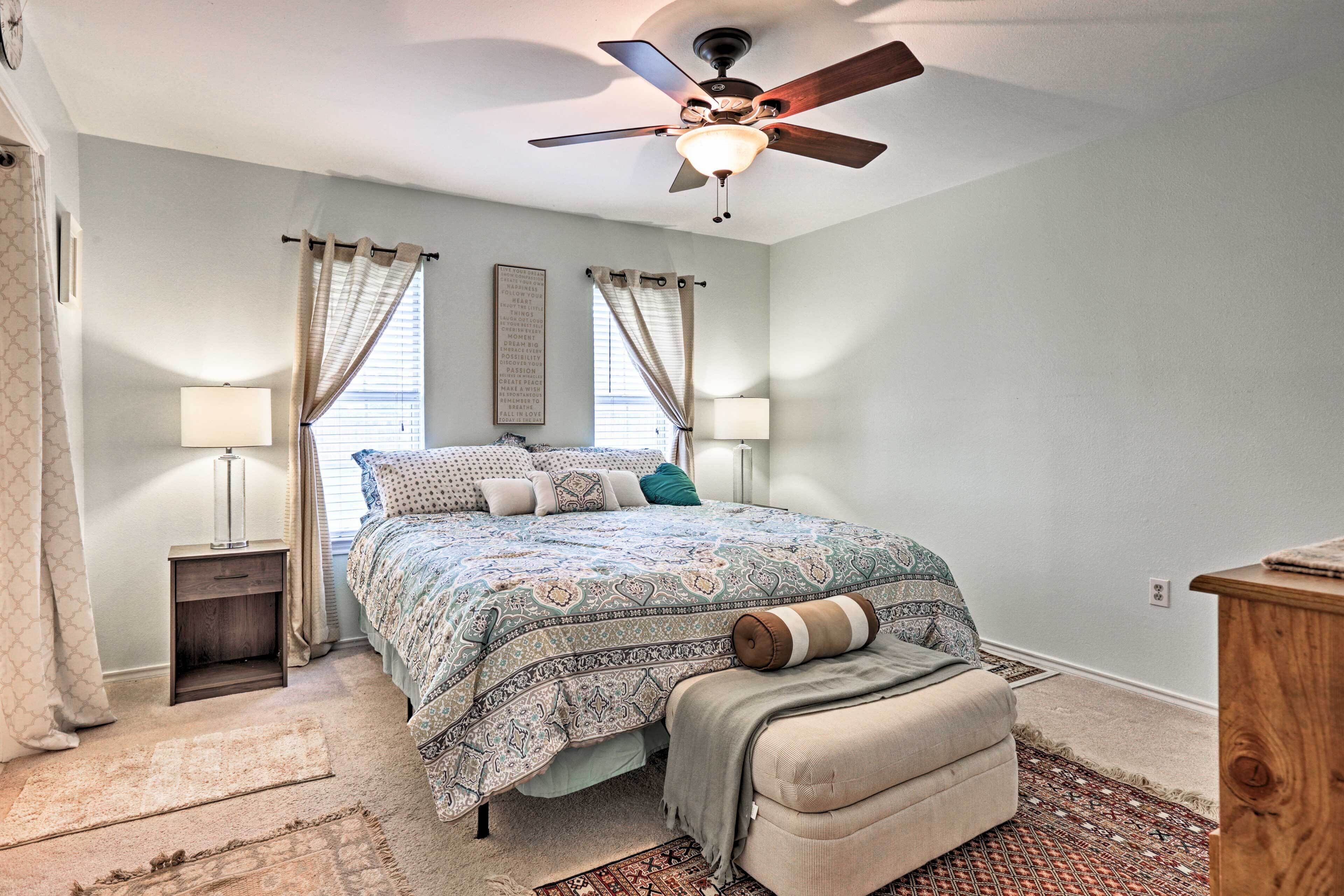 A bedroom with a bed, bedside lamps, a ceiling fan, and a rug.
