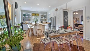 A modern kitchen with white cabinets, a central island, and a dining area with striped chairs. - Walk to Downtown: Pet-friendly Millerton Home! (Millerton)
