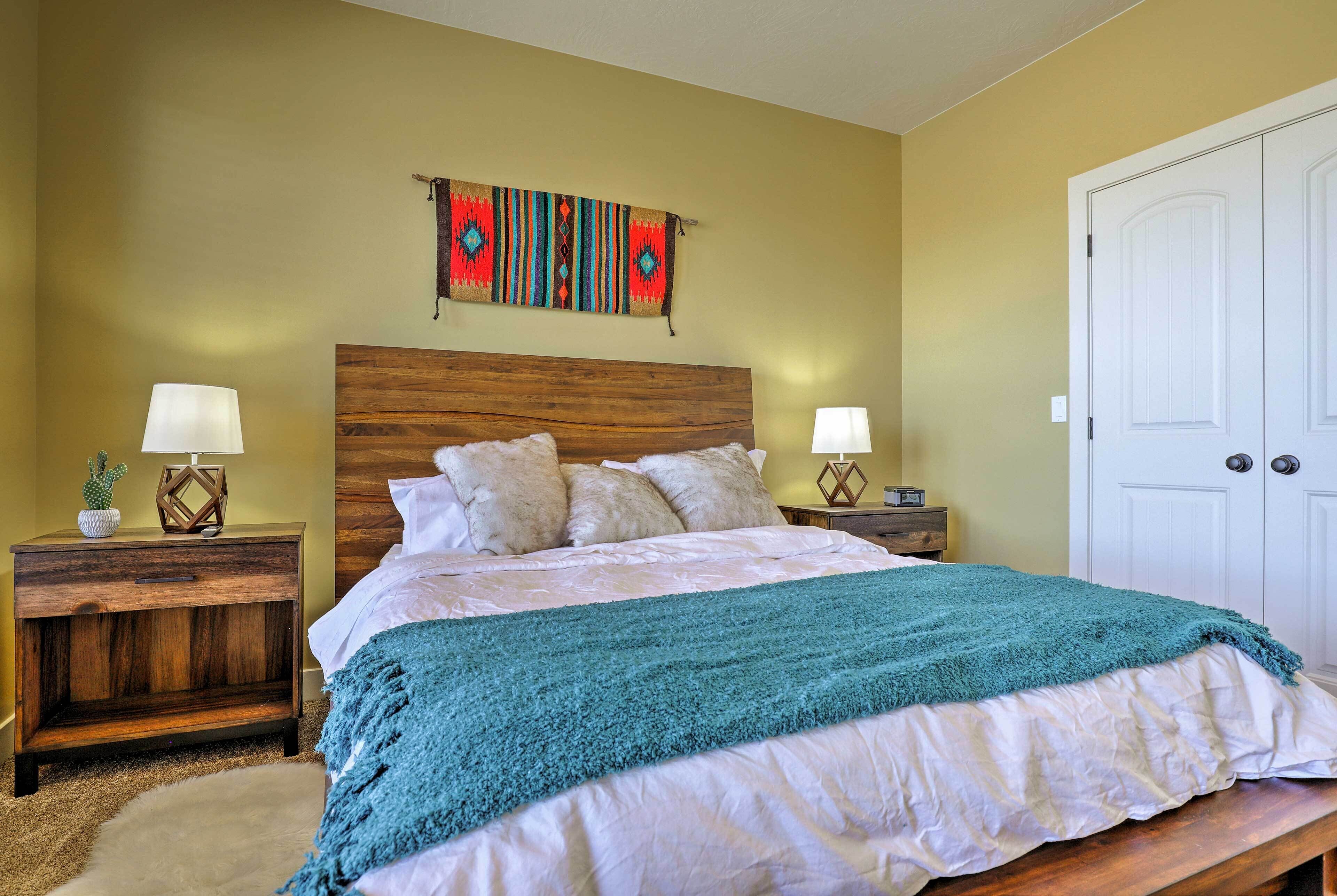 A bedroom with a wooden headboard, a teal throw blanket, and two bedside tables with lamps.