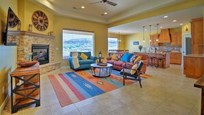 A spacious living room with a fireplace, sofas, and a view of the outdoors. - La Verkin Home w/ Hot Tub, Kayaks, & Bikes! (La Verkin)