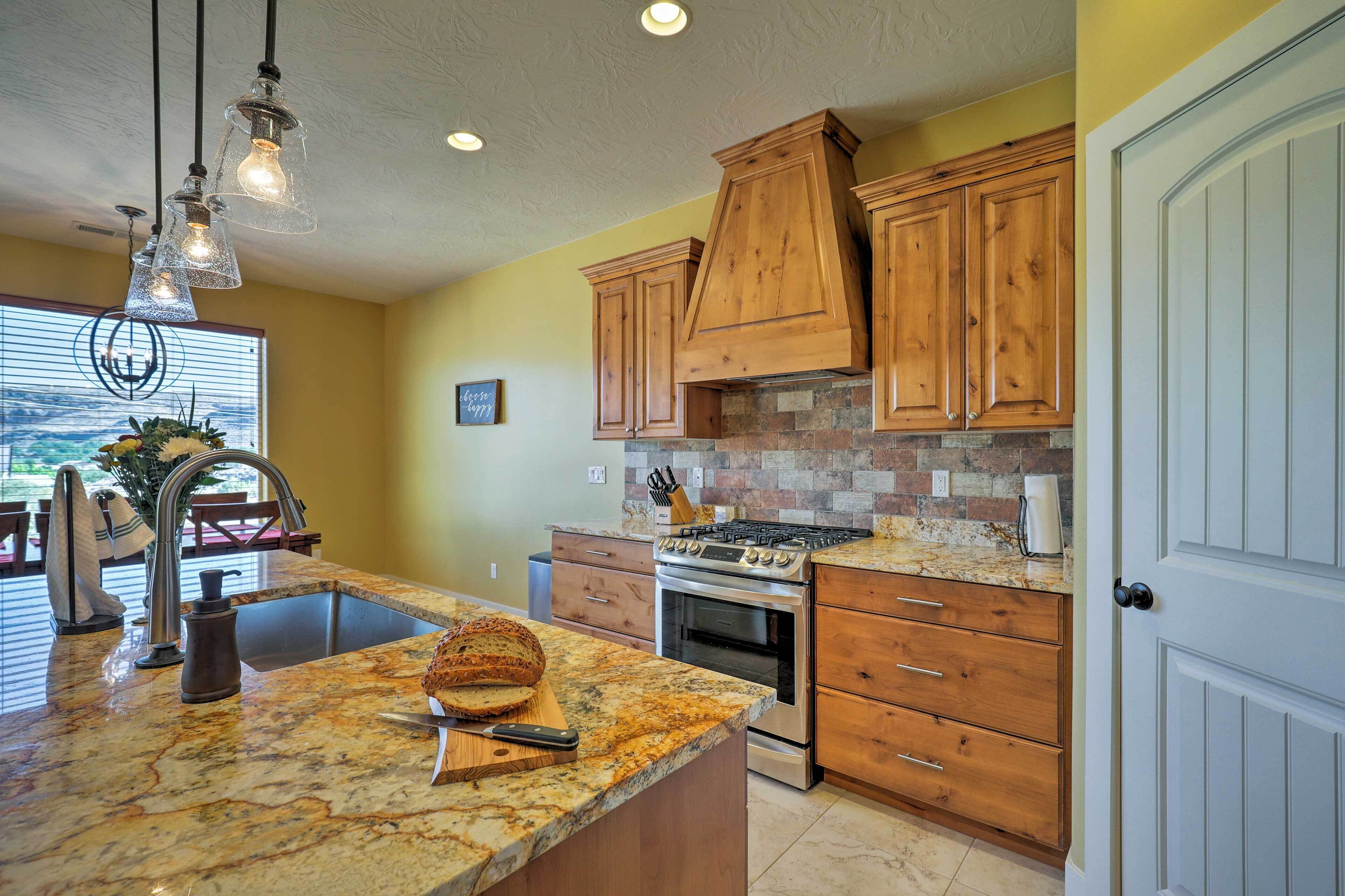 A kitchen with granite countertops, wooden cabinets, a built-in stove, and a large window with blinds.