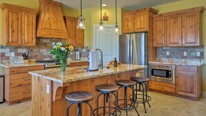 A kitchen with wooden cabinets, a granite countertop, a stainless steel refrigerator, and a built-in microwave. - La Verkin Home w/ Hot Tub, Kayaks, & Bikes! (La Verkin)