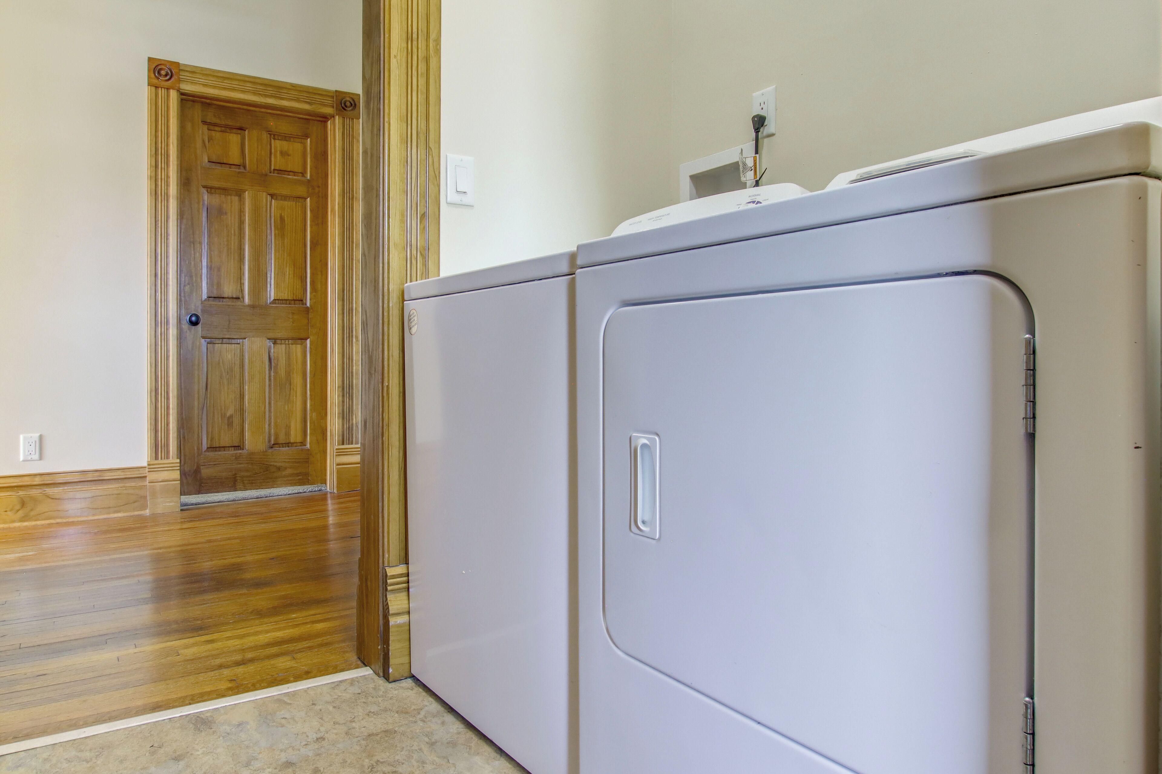 Un lavadero con una puerta de madera y una lavadora blanca.
