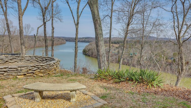 A stone bench surrounded by a gravel area with a view of a river and trees. - Lake Cumberland Resort Condo w/ Direct Lake Access (Bronston)