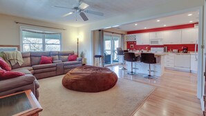 A modern living room with a brown leather sofa, a brown ottoman, and a ceiling fan. - Lake Cumberland Resort Condo w/ Direct Lake Access (Bronston)
