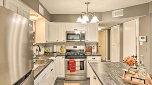 A modern kitchen with stainless steel appliances, white cabinetry, and a granite countertop. - Fort Worth Retreat w/ Fenced Yard & Fire Pit! (Fort Worth)