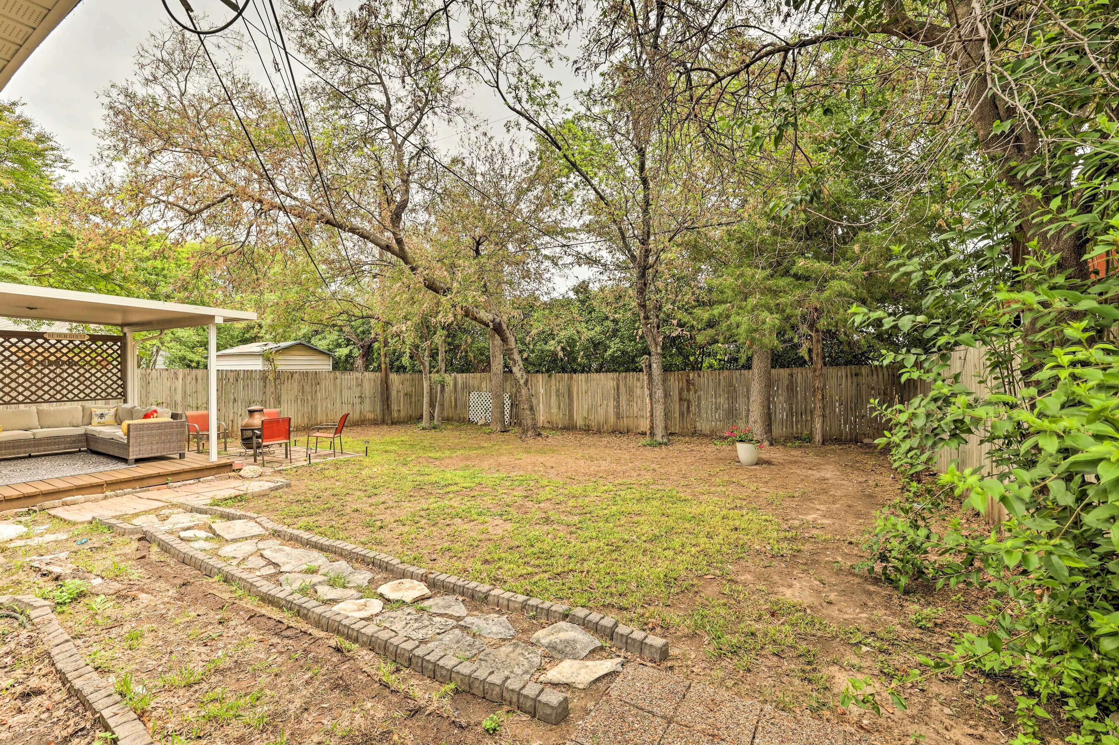 A backyard with a patio, a covered seating area, and a wooden fence.