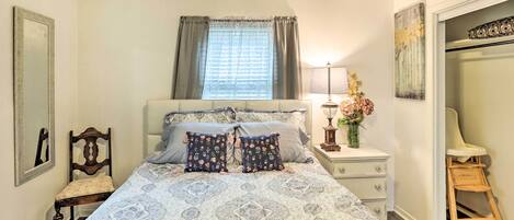 A bedroom with a bed, bedside table, lamp, chair, and a mirror.