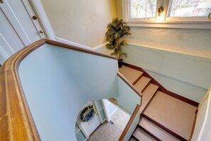 A staircase with a wooden handrail, a potted plant, and a wreath on the landing.