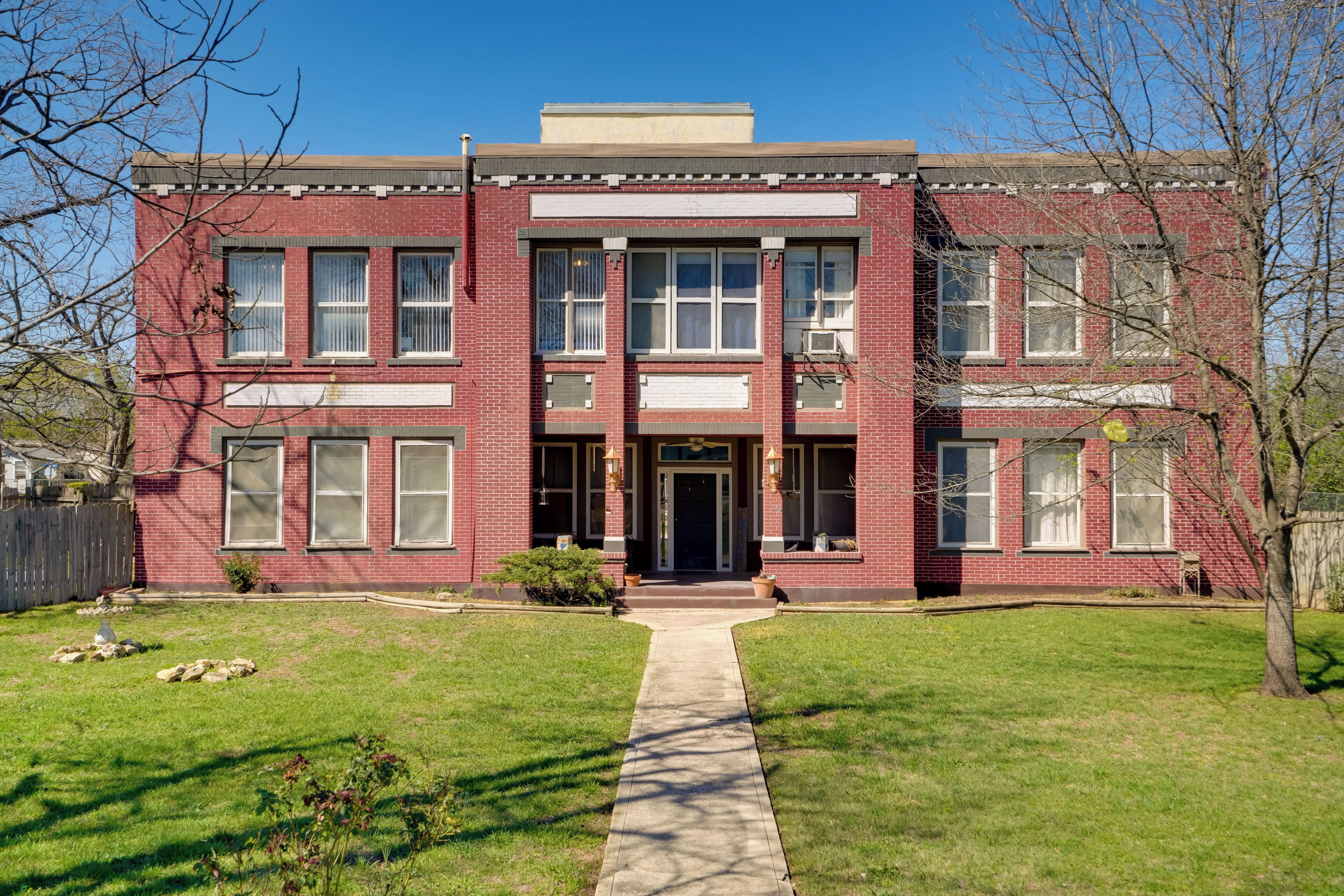 A red brick building with a central entrance, large windows, and a symmetrical facade.