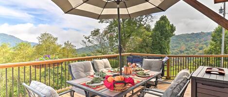 A deck with a table set for dining, outdoor chairs, and a large umbrella.