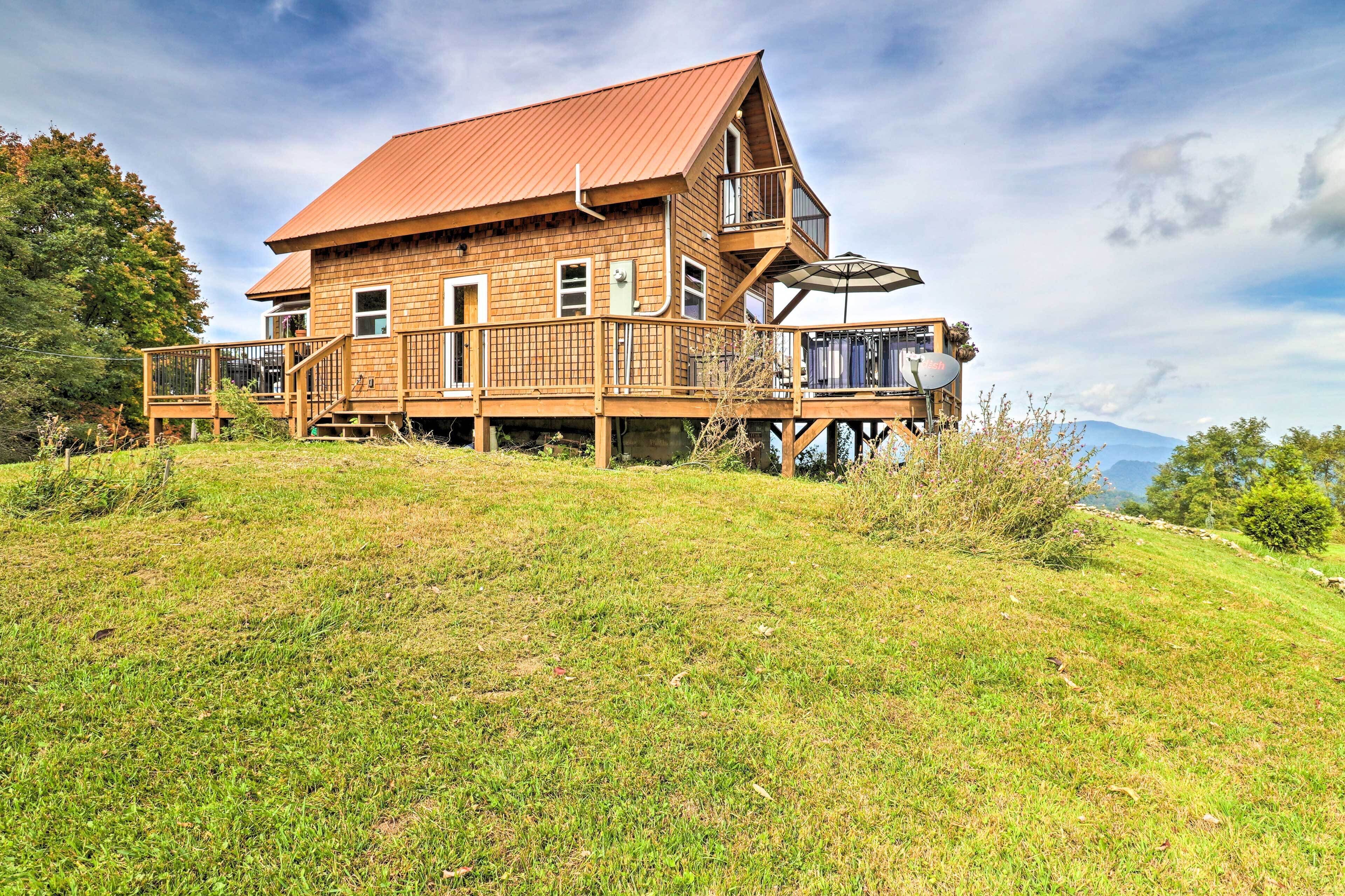 Una casa de madera con balcón, terraza y vistas a la montaña.