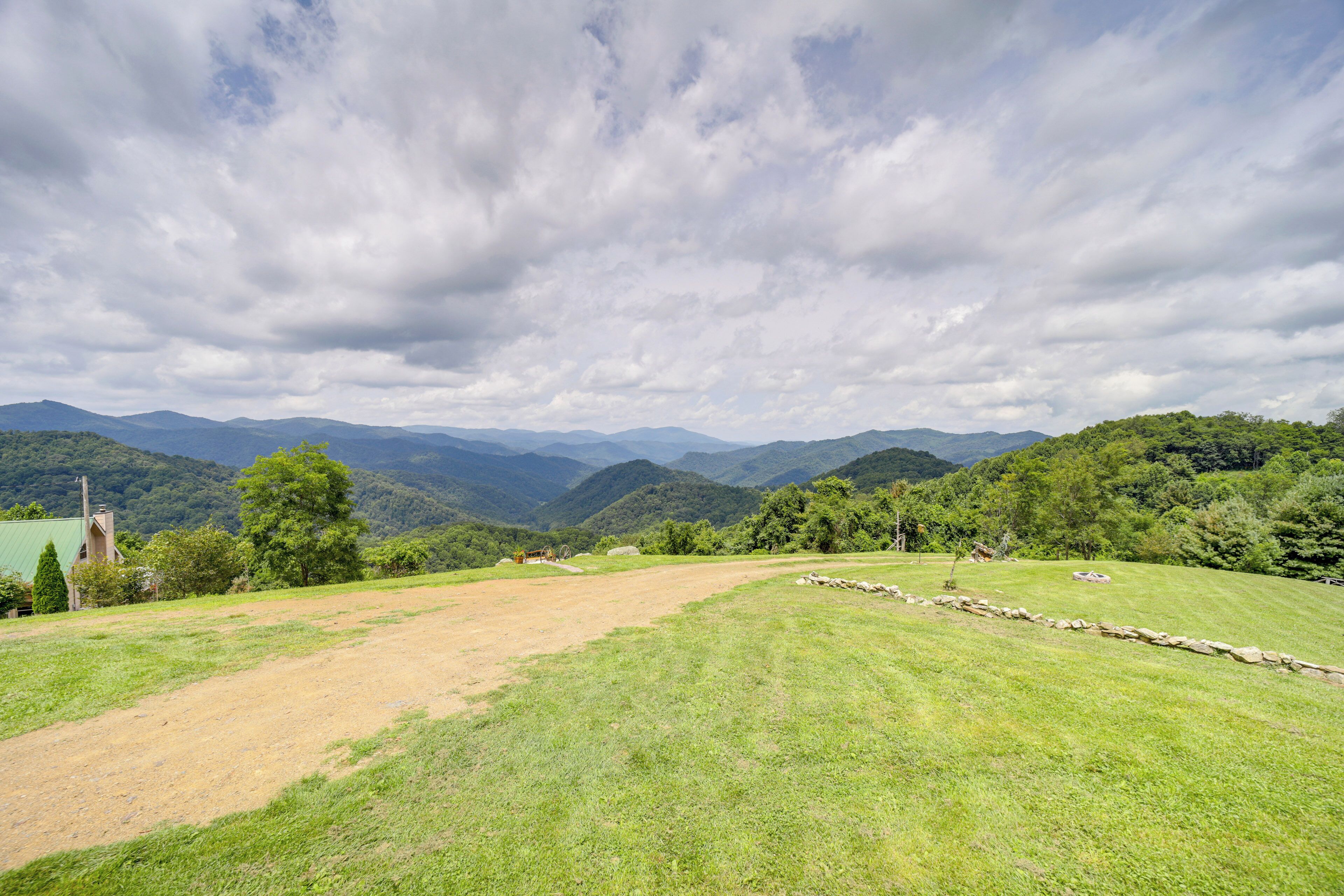 A panoramic view of a lush green landscape with rolling hills and a stone wall in the foreground.