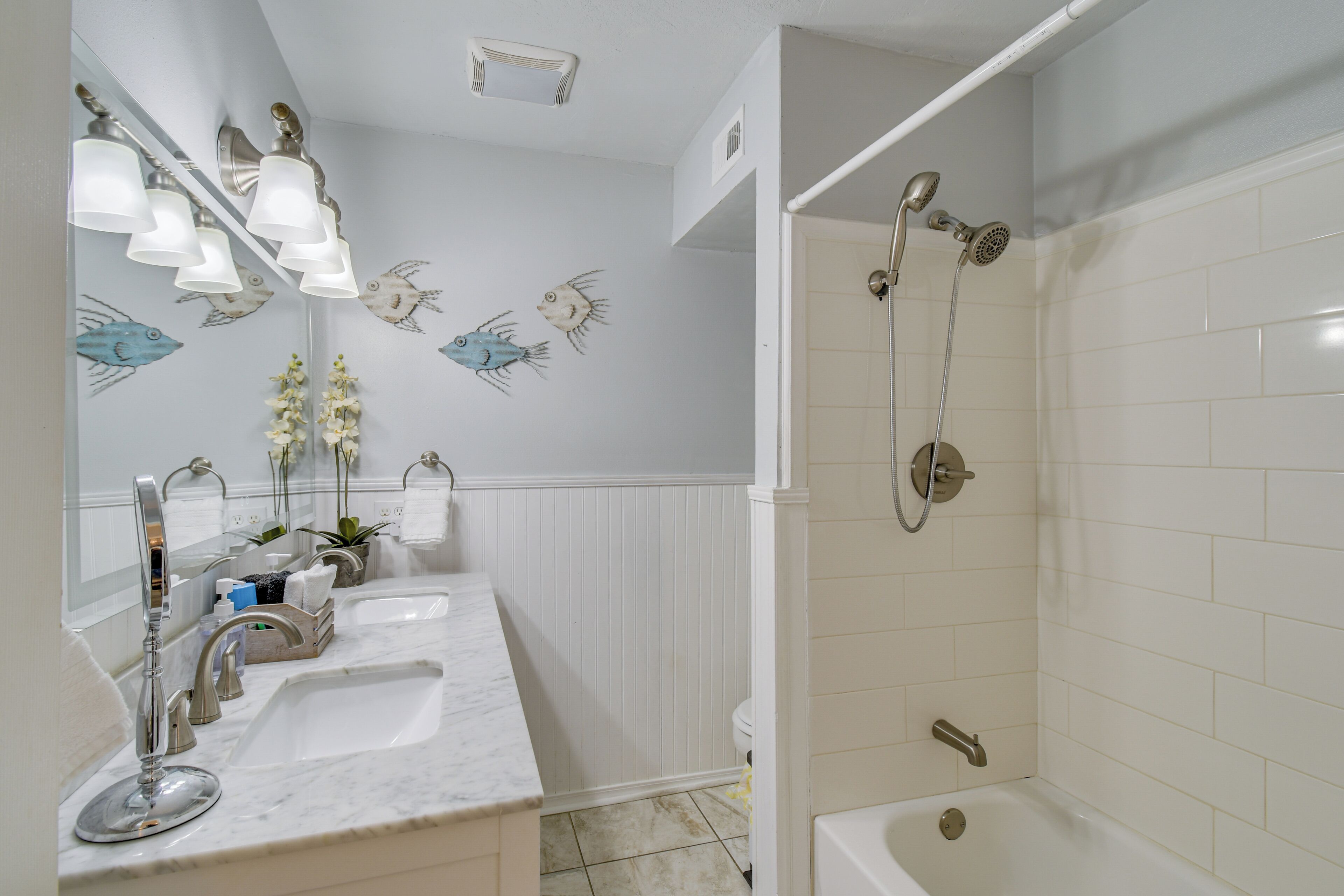 Une salle de bain avec un meuble-lavabo, une douche et des luminaires fixés au mur.