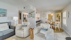 A living room with a sofa, armchairs, a coffee table, a dining area with a table and chairs, and a kitchen in the background. - Oceanfront Gulf Shores Condo ~ 2 Mi to The Hangout (Gulf Shores)