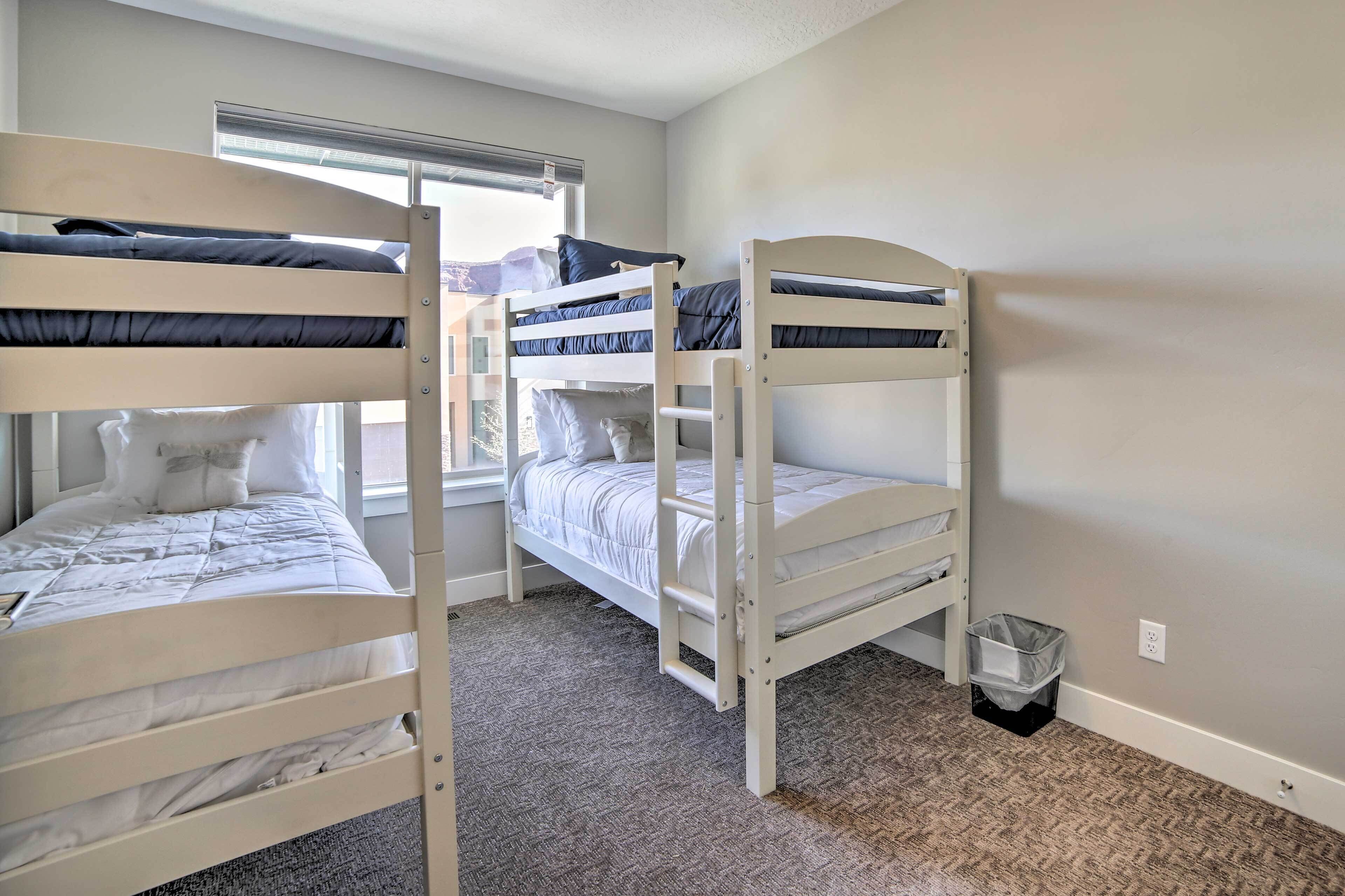 Une chambre avec deux lits superposés, une fenêtre et un sol recouvert de moquette.