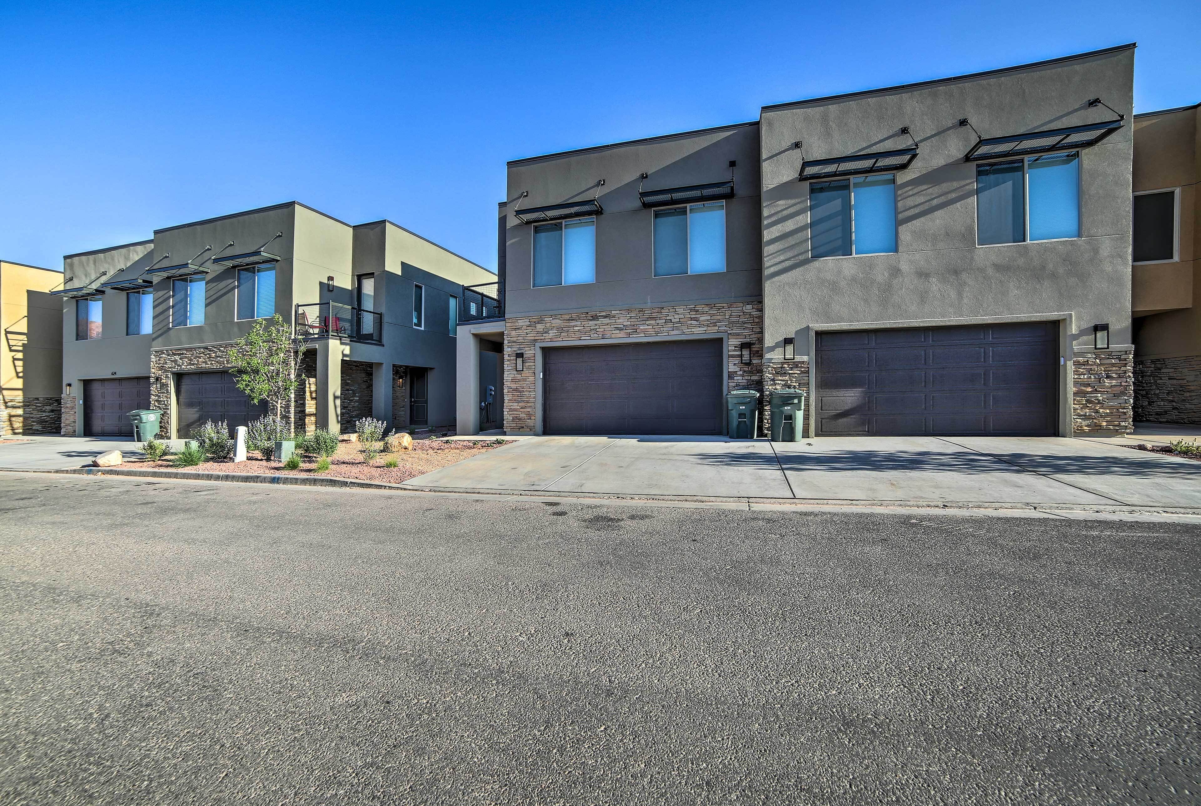 A row of modern two-story houses with garage doors, a clear sky, and a well-maintained driveway.