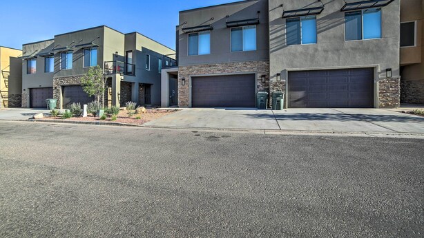 A row of modern two-story houses with garage doors, a clear sky, and a well-maintained driveway. - Luxury Moab Vacation Rental w/ Pool Access! (Moab)