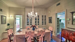 A dining room with a chandelier, a table set for four, and a view of the outside. - Walk to Main St Action! Spacious Historic Retreat (Fredericksburg)