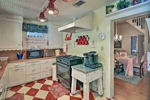 A kitchen with a stove, microwave, and cabinets. There is a dining area with a table and chairs.