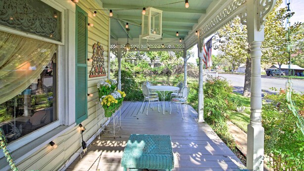 A porch with a table and chairs, a hanging lantern, and a view of the street. - Walk to Main St Action! Spacious Historic Retreat (Fredericksburg)
