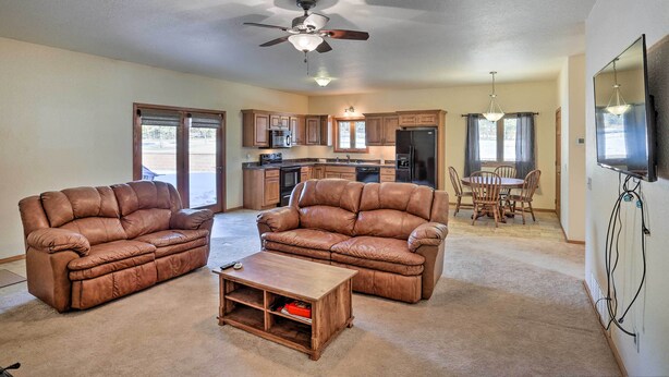 A spacious living room with a brown leather sofa set, a wooden coffee table, and a ceiling fan.