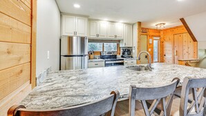 A kitchen with a marble countertop, wooden cabinets, and a stainless steel refrigerator. - Pristine Resort Townhome 2 Mi to Seven Springs Mtn (Champion)