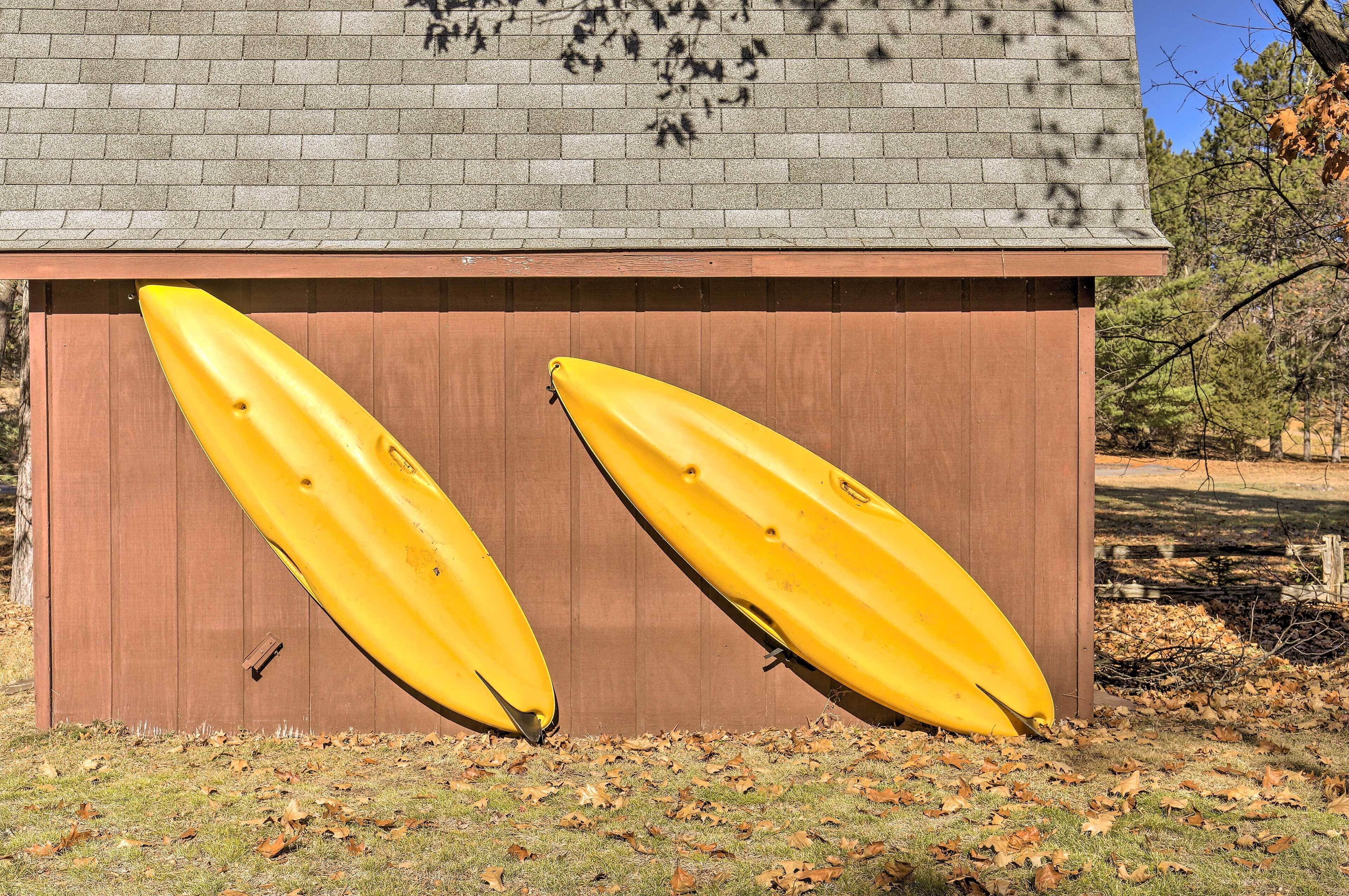 Deux kayaks jaunes sont appuyés contre une remise en bois dont le toit est fait de briques.