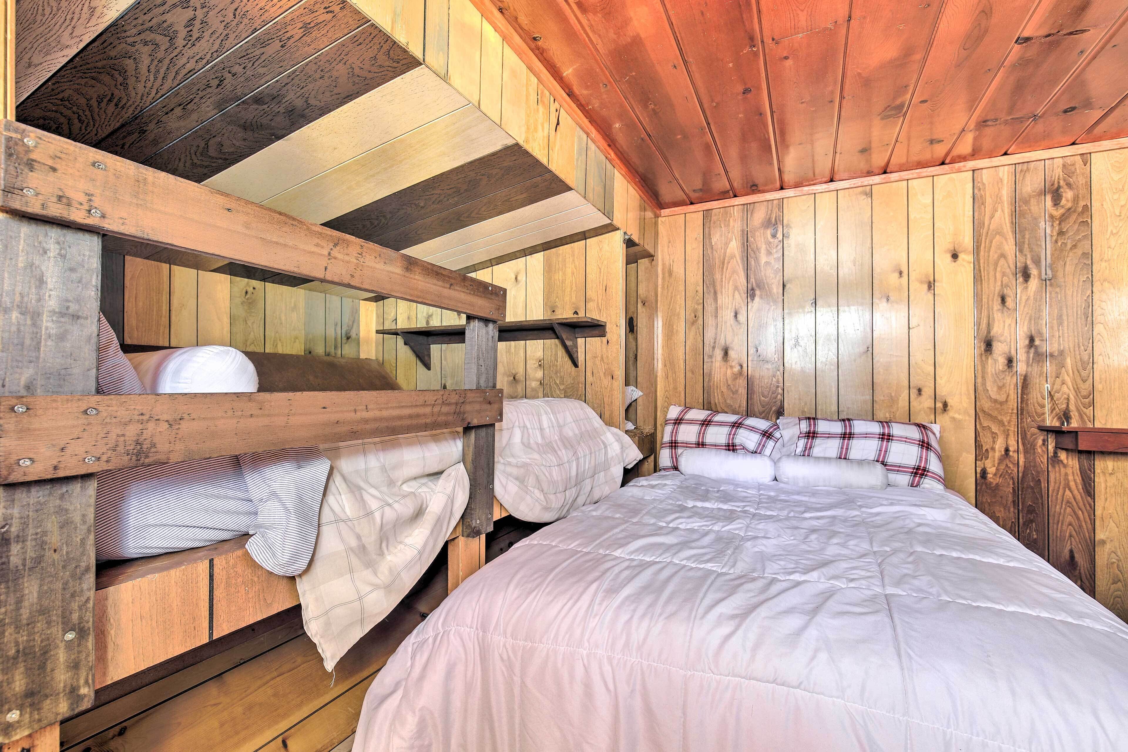 Een houten kamer in blokhutstijl met stapelbedden en een enkele bed.