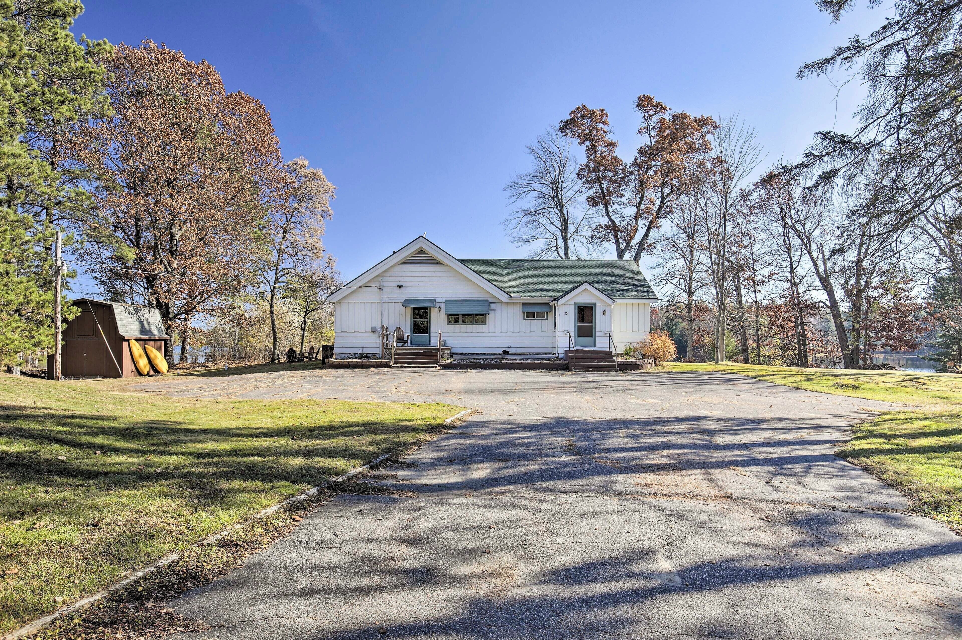 A single-story white house with a green roof, a front porch, and a driveway leading to the entrance.