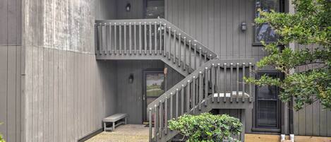Ein zweistöckiges Gebäude mit einer Holztreppe und einem kleinen Garten.